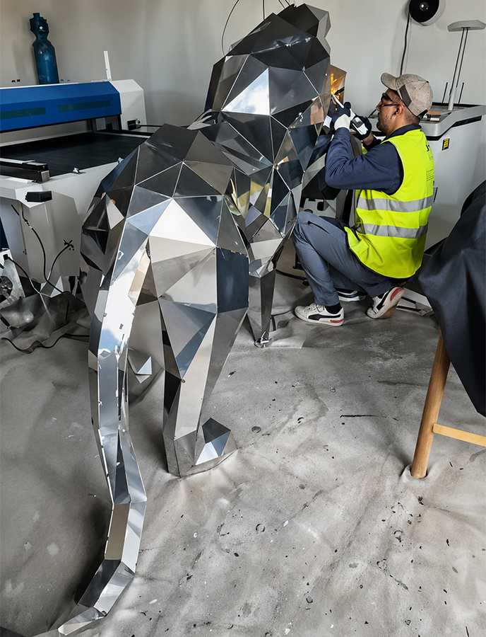 Artisan assemblant une sculpture de gorille facettée en inox dans un atelier à Casablanca