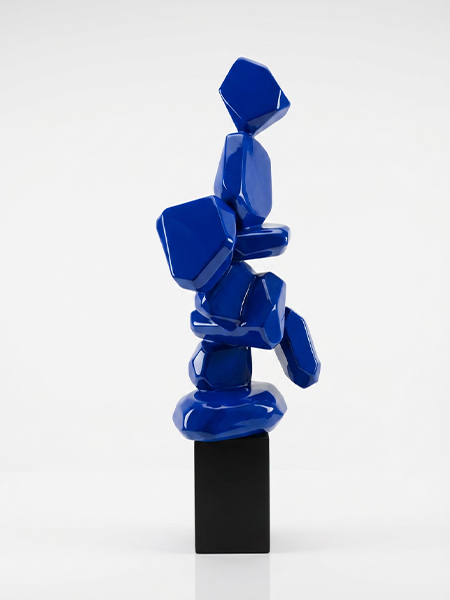 Sculpture abstraite en résine bleue brillante composée de volumes organiques sur un socle noir